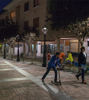 People are walking around on the Palencia streets at night lit by Philips lighting