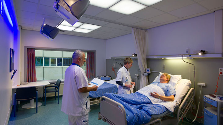 Doctors taking care of a patient in a room lighting up with Philips Healwell lighting system