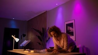 ไฟ LED อัจฉริยะ Philips Hue สร้างบรรยากาศสีม่วงและสีชมพูที่สดใสในห้องนั่งเล่น พร้อมหลอดไฟและอุปกรณ์แสงสว่างที่ปรับแต่งได้สำหรับค่ำคืนแห่งการชมภาพยนตร์และการพักผ่อนในบ้านสมัยใหม่