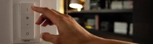 "มือที่ปรับสวิตช์ปรับความสว่าง LED อัจฉริยะของ Philips ช่วยควบคุมหลอดไฟและอุปกรณ์แสงสว่างในห้องนั่งเล่นอันแสนสบายพร้อมชั้นวางหนังสือ"