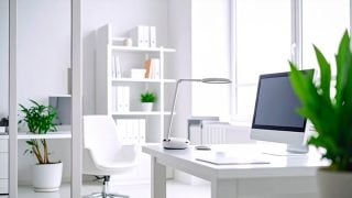 ห้องสีขาวสว่างมีโต๊ะที่มีคอมพิวเตอร์และโคมไฟตั้งโต๊ะวางอยู่